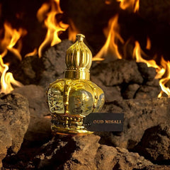 OUD MISALI Arabian attar in a luxurious golden crown bottle against a backdrop of flames and rocks.