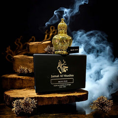 Bottle of Jamal Al Muslim Blue Oud attar on wooden logs with smoke, showcasing luxury Arabian perfume.