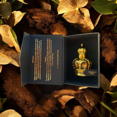 Tobacco Oud 12ml bottle presented in open box surrounded by dry leaves, showcasing luxurious Arabian perfume oil.
