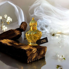 Ameer Al Oud fragrance bottle on wooden surface with soft smoke background, showcasing its luxurious design.