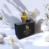 Elegant White Oud attar bottle by Jamal Al Muslim, presented with flowers and stones, showcasing refined fragrance.