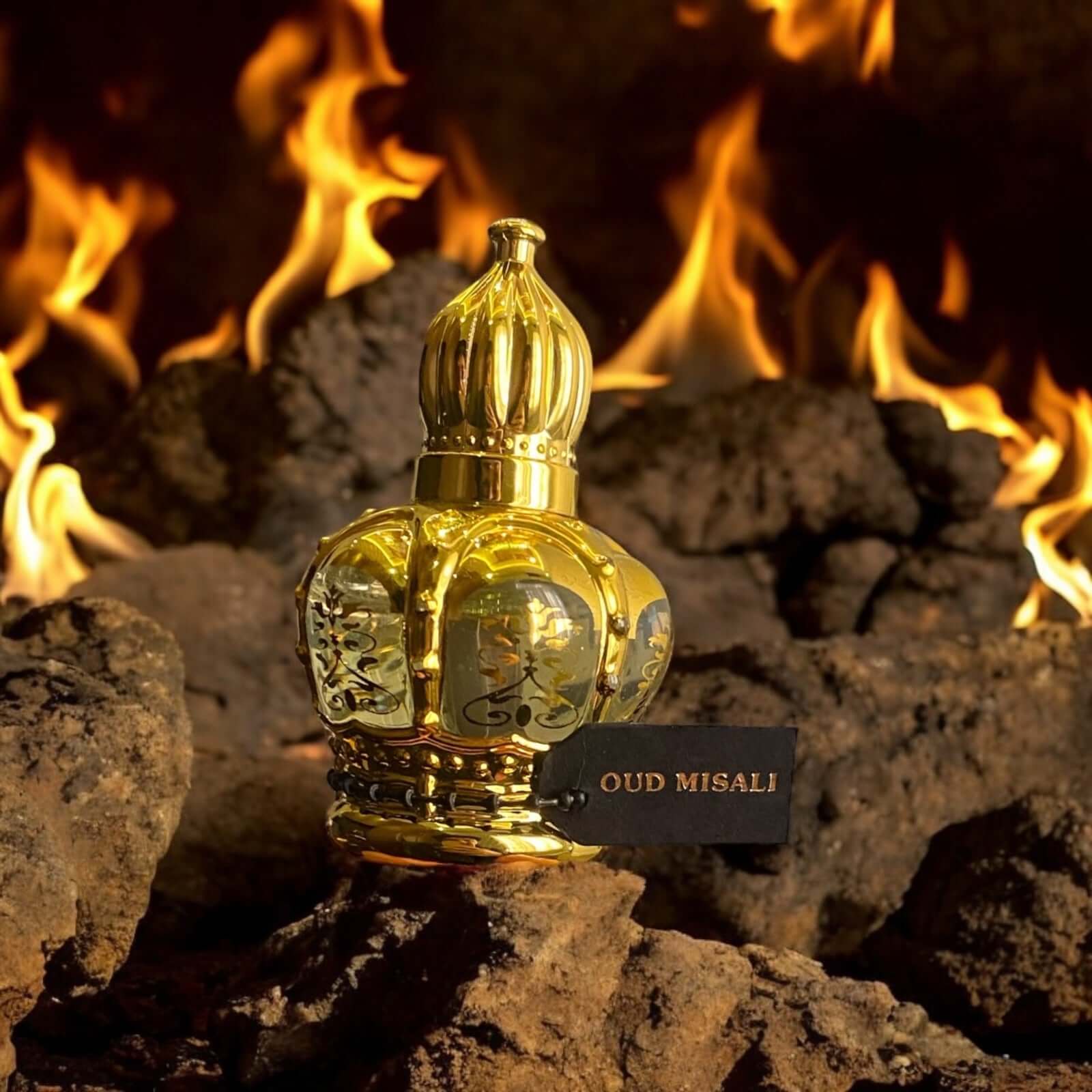 OUD MISALI Arabian attar in a luxurious golden crown bottle against a backdrop of flames and rocks.