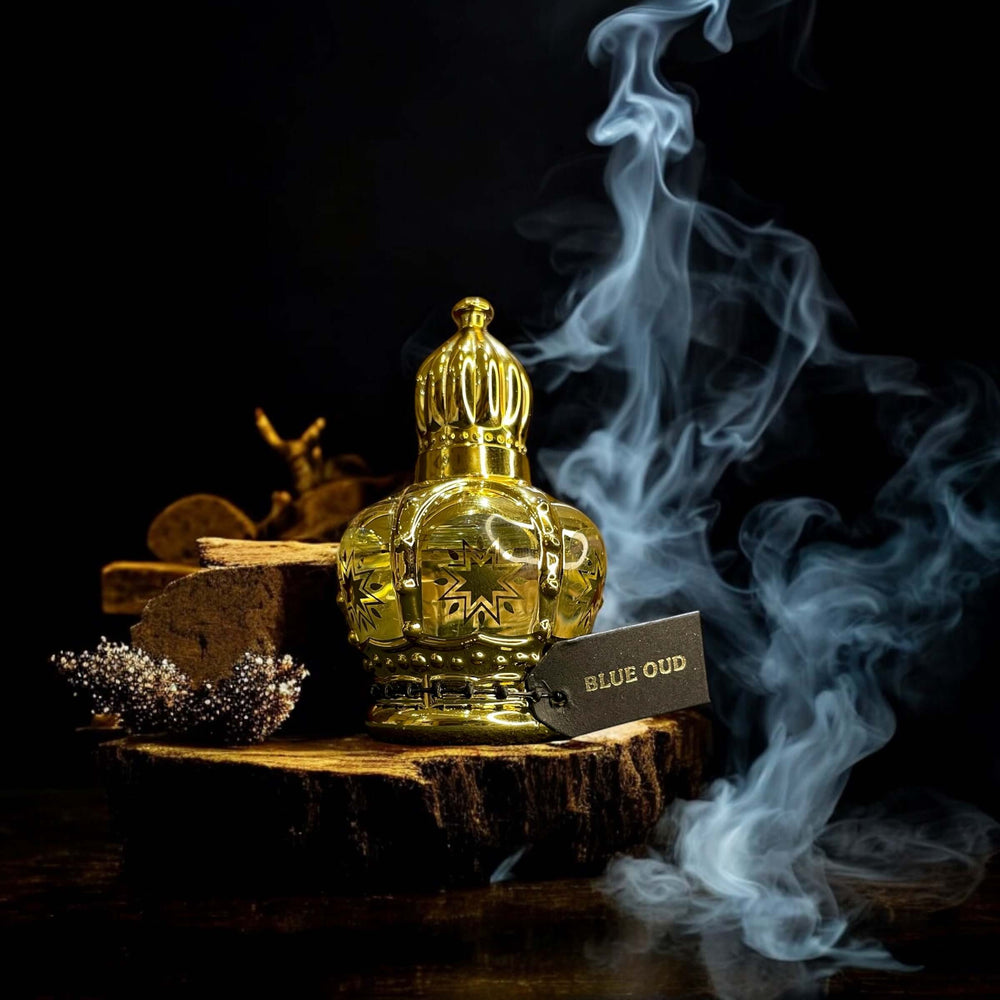 Golden bottle of Saudi Arabian Blue Oud perfume oil surrounded by smoke on a wooden base.